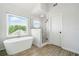 Bright bathroom showcasing a luxurious soaking tub and frameless glass shower with tile surround and window at 200 Glen Wood Place, Canton, GA 30114