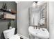 Contemporary bathroom featuring a pedestal sink, toilet, shelving, decorative mirror, and modern finishes, optimizing space and style at 2653 W Main Nw St, Atlanta, GA 30318