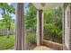 Covered porch with brick columns, a ceiling fan, and privacy curtains overlooking the wooded yard at 4046 Newhaven Ne Cir, Atlanta, GA 30319