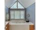 A light and airy bathroom featuring a soaking tub beneath large windows and classic wallpaper at 711 Belgrave Ln, Tucker, GA 30084