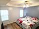 Serene main bedroom featuring a ceiling fan, a tray ceiling, wood-look floors, and ample natural light at 102 Ashbury Dr, Villa Rica, GA 30180