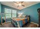 Bedroom featuring a ceiling fan, blue walls, carpeted floors and a large window at 3291 Wild Basil Ln, Buford, GA 30519