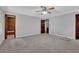 Large bedroom with neutral walls, plush carpeting, ceiling fan, and three wooden doors at 6896 Heardsville Rd, Cumming, GA 30028