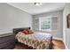 A cozy bedroom with hardwood floors, gray walls, and natural light from a window at 1908 E Roxboro Ne Rd, Atlanta, GA 30324