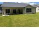 Backyard with large grassy area, a covered patio with pillars, and sliding glass doors to inside at 313 Sobeck Way, Canton, GA 30115
