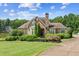 Charming home exterior with stone accents and lush landscaping, set against the backdrop of a tranquil lake at 317 Red Gate Overlook, Canton, GA 30115
