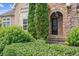Close-up of a home's stone entrance, arched doorway, and manicured bushes along the walkway at 317 Red Gate Overlook, Canton, GA 30115