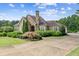 Attractive home featuring a stone chimney, arched entryway, manicured shrubs, and a spacious concrete driveway at 317 Red Gate Overlook, Canton, GA 30115