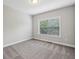 Simple bedroom with neutral carpet, walls, and a view to the outdoors at 3705 Williams Point Dr, Cumming, GA 30028