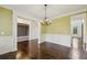 Open dining room featuring hardwood floors, wainscoting, and a decorative light fixture at 3705 Williams Point Dr, Cumming, GA 30028