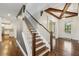 Elegant staircase with wooden steps, white railings, and an open view of the kitchen at 3705 Williams Point Dr, Cumming, GA 30028