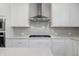 Close up of stovetop, stainless steel hood, white cabinets, and quartz countertops at 6934 Melody Ridge Rd, Buford, GA 30518