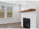 Close up of a fireplace with white shiplap detail, wooden mantle, and a wall of windows at 6934 Melody Ridge Rd, Buford, GA 30518