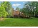 Brick home's backyard with a deck, large lawn, mature trees, and stairs leading up to a wooden fence at 240 Old Plantation Way, Fayetteville, GA 30214