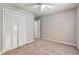 Bedroom with double door closet, neutral color palette, soft carpet, and ceiling fan at 5215 Mainstreet Park Dr, Stone Mountain, GA 30088