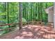 Deck featuring wood railing and a backdrop of lush green trees at 5215 Mainstreet Park Dr, Stone Mountain, GA 30088