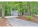 View of a home's garage and a winding driveway surrounded by lush trees and greenery at 5215 Mainstreet Park Dr, Stone Mountain, GA 30088