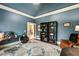 Well-appointed home office with blue walls, dark wood trim, built-in shelving, and large patterned area rug at 217 Fernwood Pl, Woodstock, GA 30188