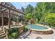 Beautiful stone pool and hot tub surrounded by mature landscaping and brick pavers at 217 Fernwood Pl, Woodstock, GA 30188