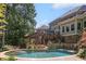 A luxurious backyard oasis features a stone patio, cascading waterfall, covered deck, and large inground pool at 217 Fernwood Pl, Woodstock, GA 30188