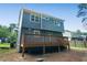 View of the home's backyard featuring a wooden deck and gray siding against a backdrop of lush trees at 597 Woodcrest Manor Dr, Stone Mountain, GA 30083