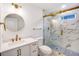 Modern bathroom featuring a white vanity, round mirror, and a marble-tiled shower with gold trim and glass doors at 597 Woodcrest Manor Dr, Stone Mountain, GA 30083