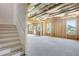 The unfinished basement has a concrete floor, exposed insulation, exposed support studs, windows, and staircase at 932 Melville Dr, Stockbridge, GA 30281