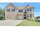 Traditional brick home with a three-car garage and well-manicured lawn under a blue sky at 932 Melville Dr, Stockbridge, GA 30281