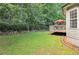 Landscaped backyard featuring a lush lawn, a wooden deck, and a retaining wall filled with greenery at 4472 Cavallon Nw Way, Acworth, GA 30101