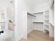 Modern walk-in closet featuring custom shelves and a glimpse into the spa-like bathroom at 125 Maison Court, Roswell, GA 30076