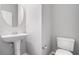 Cozy powder room featuring a pedestal sink, toilet, and a round mirror for added convenience at 2731 Pierce Brennen Ct, Lawrenceville, GA 30043