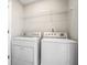 A clean laundry room equipped with a white washer and dryer, and a wire shelf at 2731 Pierce Brennen Ct, Lawrenceville, GA 30043