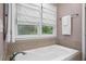 Bright bathroom featuring a soaking tub with a window, as well as tiled walls and flooring at 261 Lamplighter Se Ln, Marietta, GA 30067