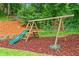 Backyard wooden playset with a slide, two swings, rings, and a tire swing surrounded by mulch at 261 Lamplighter Se Ln, Marietta, GA 30067