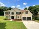 Charming two-story home featuring a well-manicured lawn and an attached two-car garage at 5159 Round Table Dr, Ellenwood, GA 30294