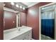Bathroom featuring a shower/tub combo with blue and white curtain, a vanity with large mirror and maroon colored walls at 168 Gatlin Ridge Run, Dallas, GA 30157