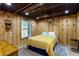 Bedroom features wooden ceiling, wood walls, a ceiling fan, queen bed with yellow floral bedding at 168 Gatlin Ridge Run, Dallas, GA 30157