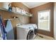 Bright laundry room equipped with modern washer and dryer, ample shelving and window for natural lighting at 168 Gatlin Ridge Run, Dallas, GA 30157