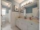 A bathroom vanity featuring white cabinets, marble countertops, a large mirror, and white wainscoting at 4188 Kindlewood Ne Ct, Roswell, GA 30075