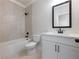 Bathroom with white cabinets, bathtub, light colored tiling, and a black framed mirror at 4436 Hosch Reserve Ct, Buford, GA 30519