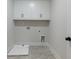 Clean laundry room with gray tile floors and white cabinets with black handles at 4436 Hosch Reserve Ct, Buford, GA 30519
