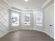 Room featuring a white patterned accent wall, neutral walls, wood floors, and three large windows at 4436 Hosch Reserve Ct, Buford, GA 30519