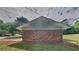 View of the back of the home from the backyard with brick foundation and green siding at 1102 Tony Valley Dr, Conyers, GA 30013