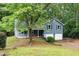 Attractive blue home with a two-car garage, complemented by mature trees and a green lawn at 4990 Turtle Rock Drive Dr, Marietta, GA 30066