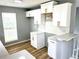 A modern kitchen boasts white cabinets, contemporary hardware, granite counters and wood-style floors at 203 Galway Ln, Hampton, GA 30228