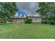 View of the back of the home showcasing a sunroom, brick facade, and large grassy backyard at 1830 Francis Sw Rd, Conyers, GA 30094