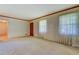 Neutral living room with light carpet, windows with lace curtains, and a wooden door at 1830 Francis Sw Rd, Conyers, GA 30094