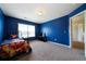 Bright bedroom featuring blue walls, carpet flooring, a window with natural light, and a bed at 303 Horizon Trce, Loganville, GA 30052