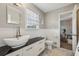 Bathroom with a modern vessel sink, black countertop, white cabinetry, wainscoting, and marble floor at 4624 Stonehenge Dr, Atlanta, GA 30360
