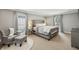 Spacious main bedroom with a luxurious upholstered bed, neutral tones, plush seating area, and bright natural light at 4624 Stonehenge Dr, Atlanta, GA 30360